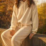Frau im cremefarbenen Hoodie-Set im Herbstlicht