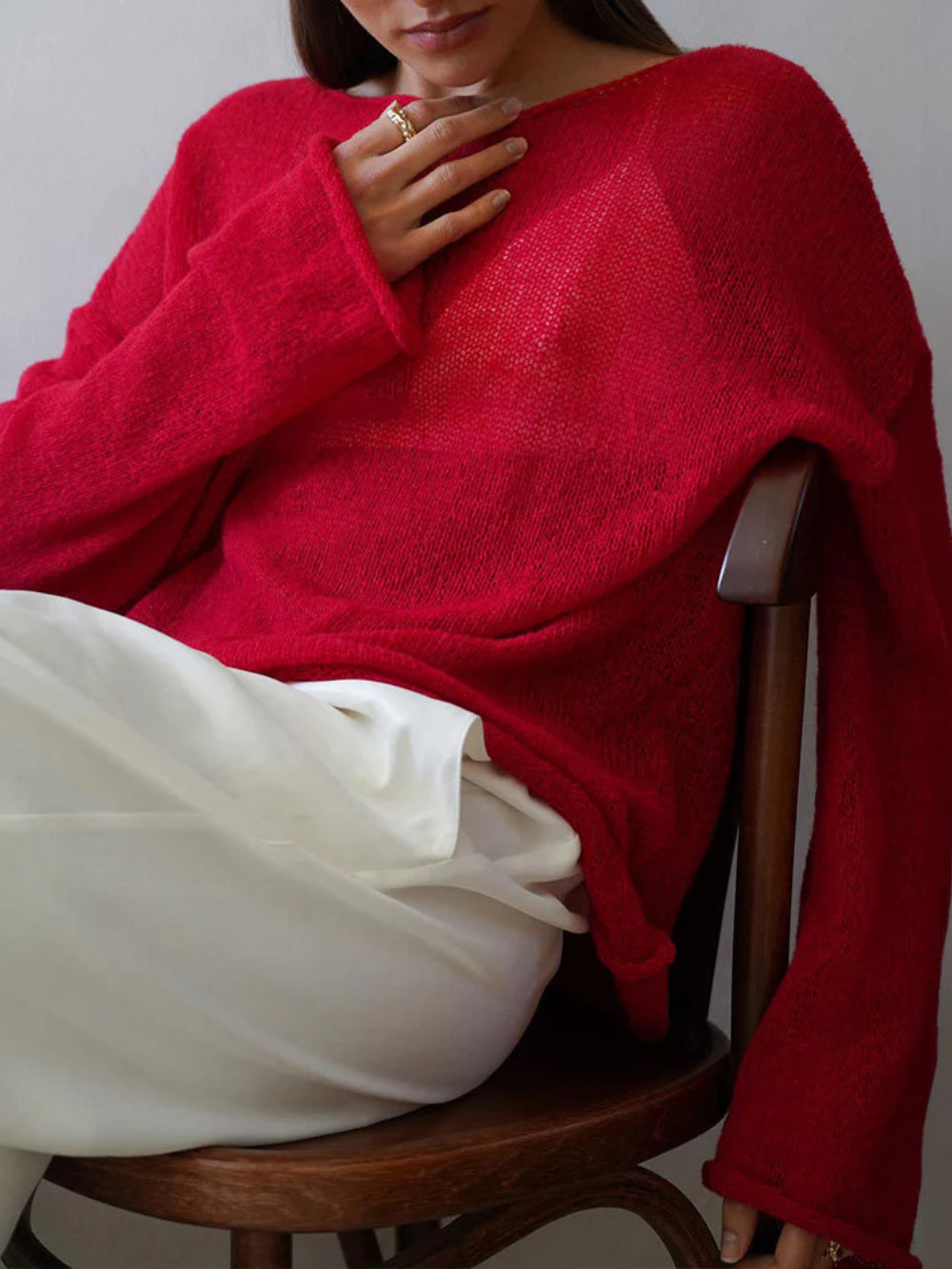 Elayne Knit in Rot, entspannt auf einem Stuhl
