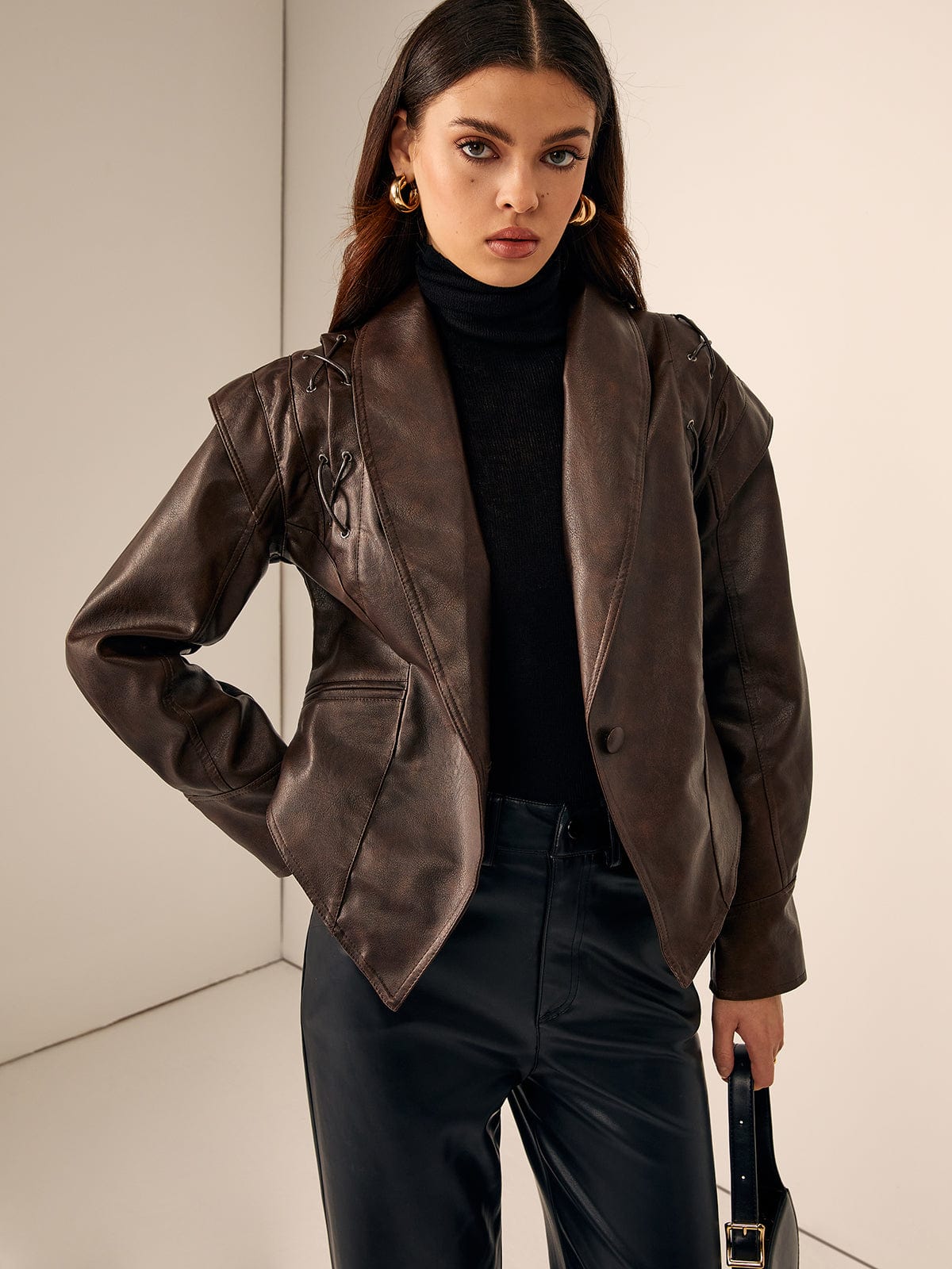 Model trägt braune Lederjacke mit Gürtel und goldenen Ohrringen