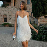 Model trägt das federbesetzte Élora Mini-Kleid in Weiß im Garten – Glamour Party Dress