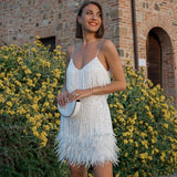 Hauptbild: Model trägt das federbesetzte Élora Mini-Kleid in Weiß im Garten – Glamour Party Dress