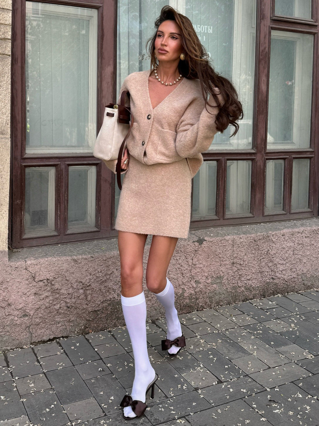 frau trägt beiges strick set mit weißen kniestrümpfen und schleifen high heels