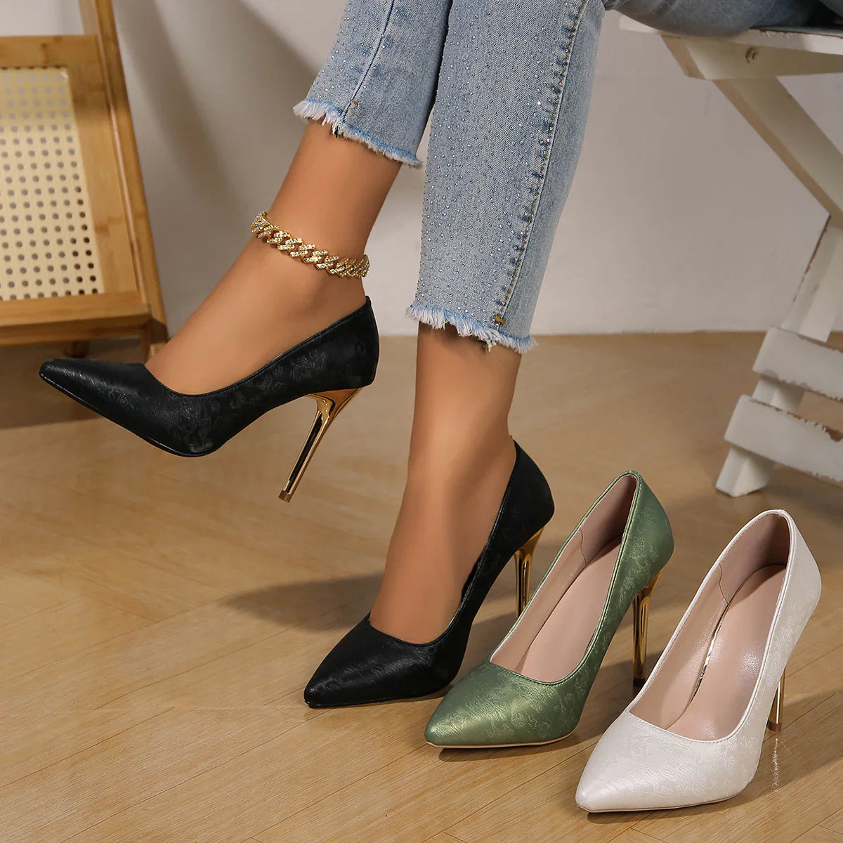 Modell trägt schwarze Satin Pumps mit goldenem Absatz zu Jeans