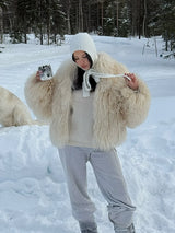 frau trägt beigen kunstpelzmantel im schnee mit weißen hosen