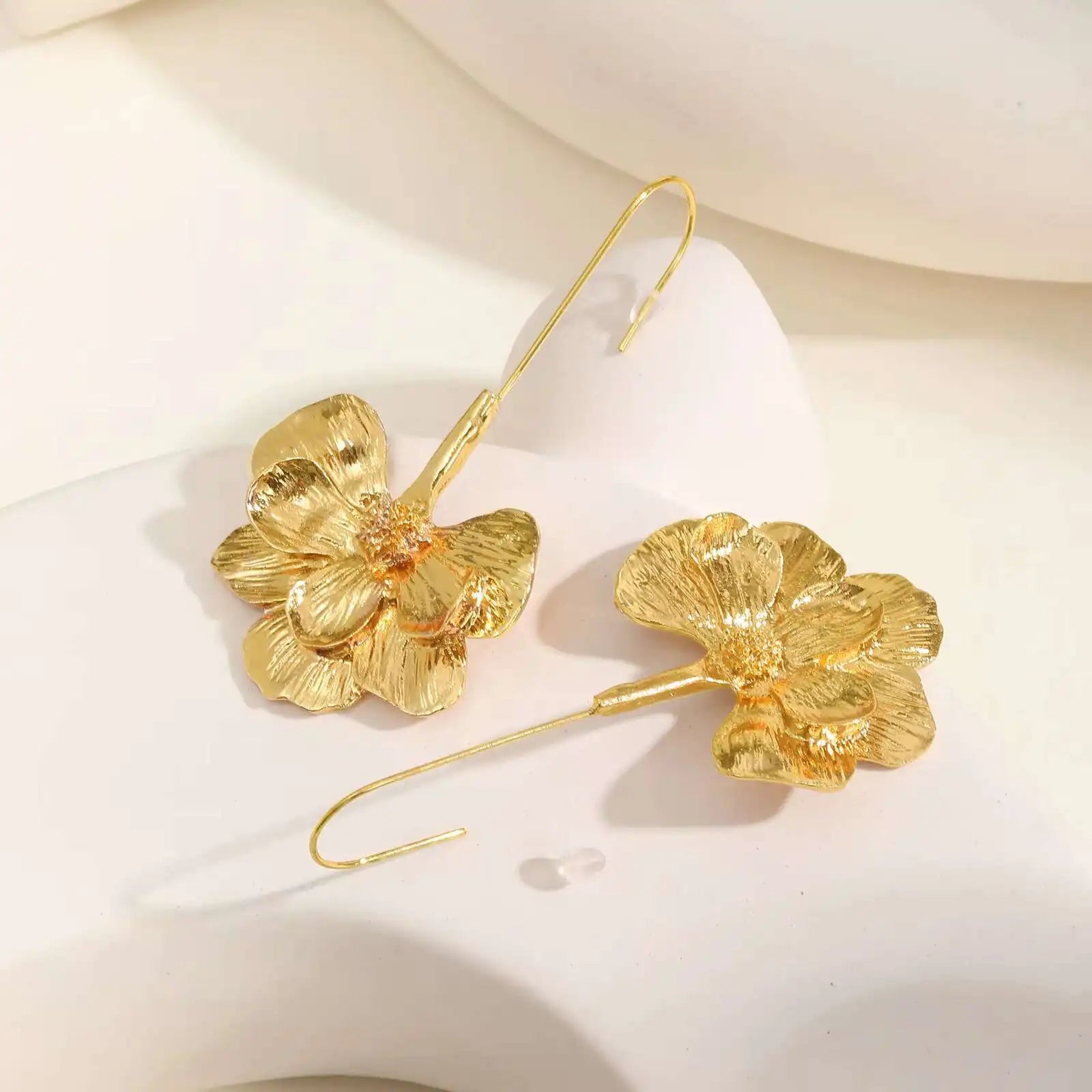 Paar goldene Blumen-Ohrringe auf hellem Hintergrund
