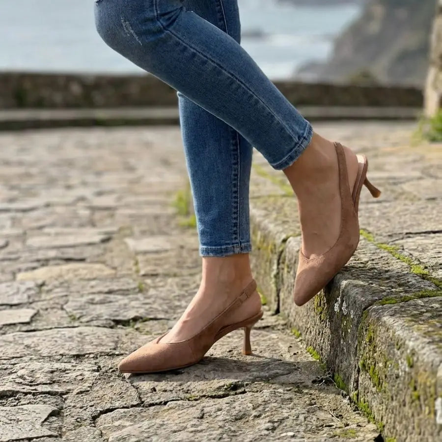Modell trägt Velmira Slingback-Pumps in Beige Wildleder, Lifestyle-Foto auf Kopfsteinpflaster