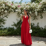 Modell in Liora Halter-Maxikleid Rot mit weißer Handtasche, Lifestyle-Foto vor weißer Wand