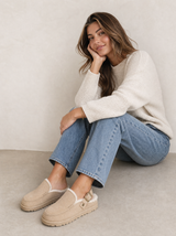 Frau in Strickpullover und Jeans trägt beige gefütterte Leder-Clogs