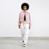 Modell trägt Rosalie Cropped Punkte-Jacke in Rosa mit schwarzen Punkten, kombiniert mit weißer Cargohose, Streetstyle-Frontansicht