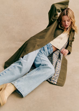 Clara Trenchcoat Oliv – liegendes Styling mit Gingham-Futter