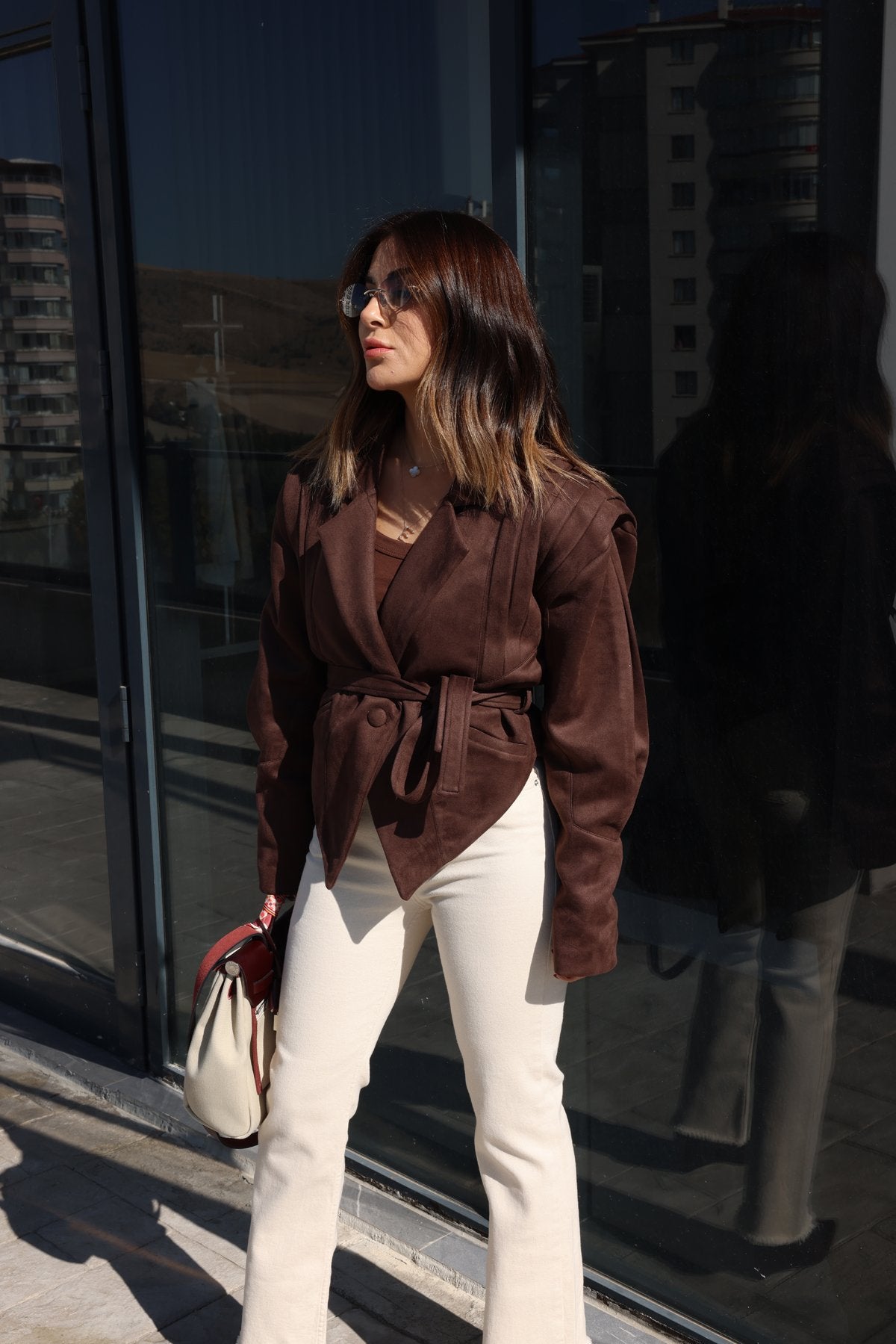 Streetstyle Look mit brauner vegane Wildlederjacke und weißer Hose